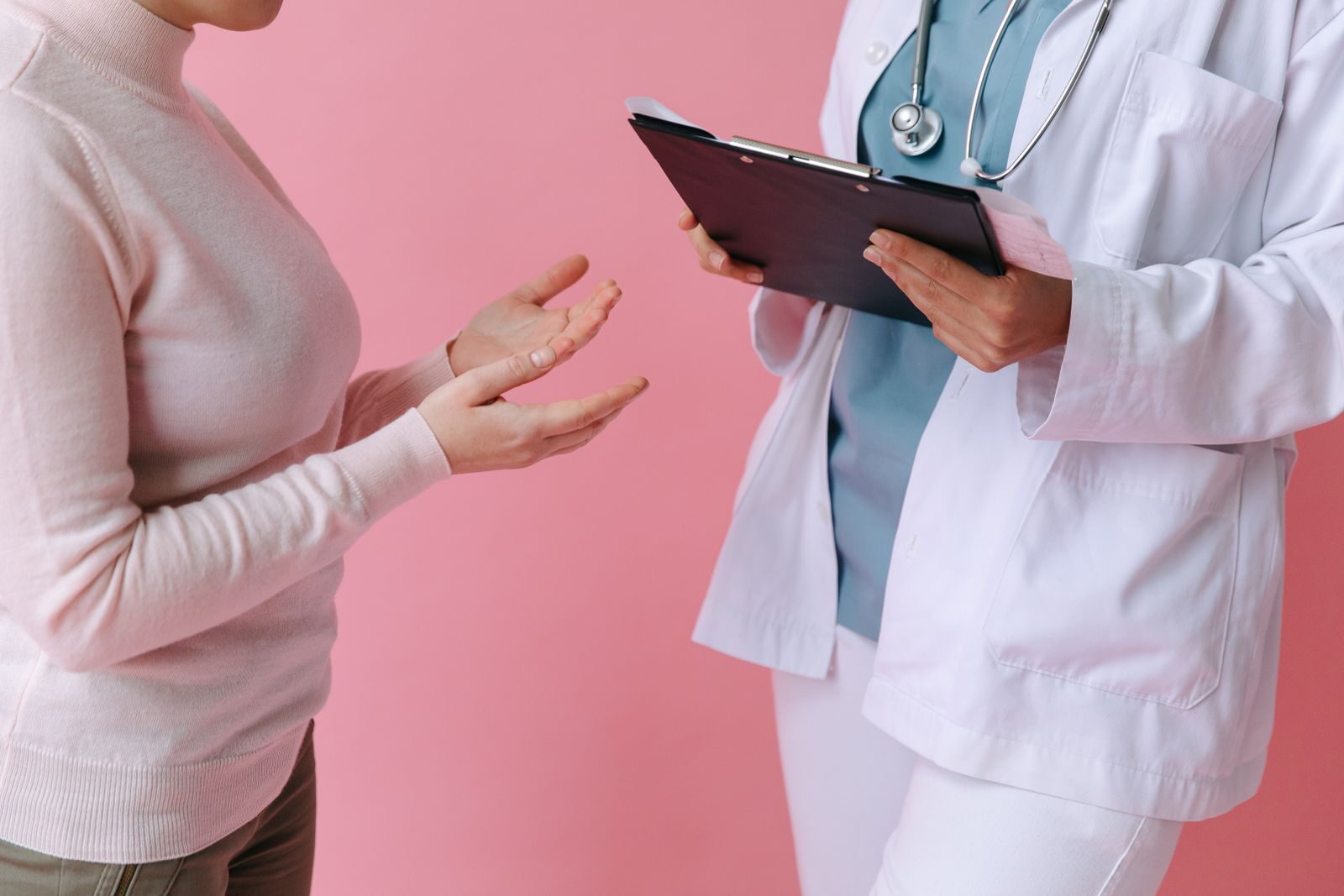 Médica conversando com uma paciente durante consulta, segurando uma prancheta, em ambiente acolhedor de clínica de saúde da mulher