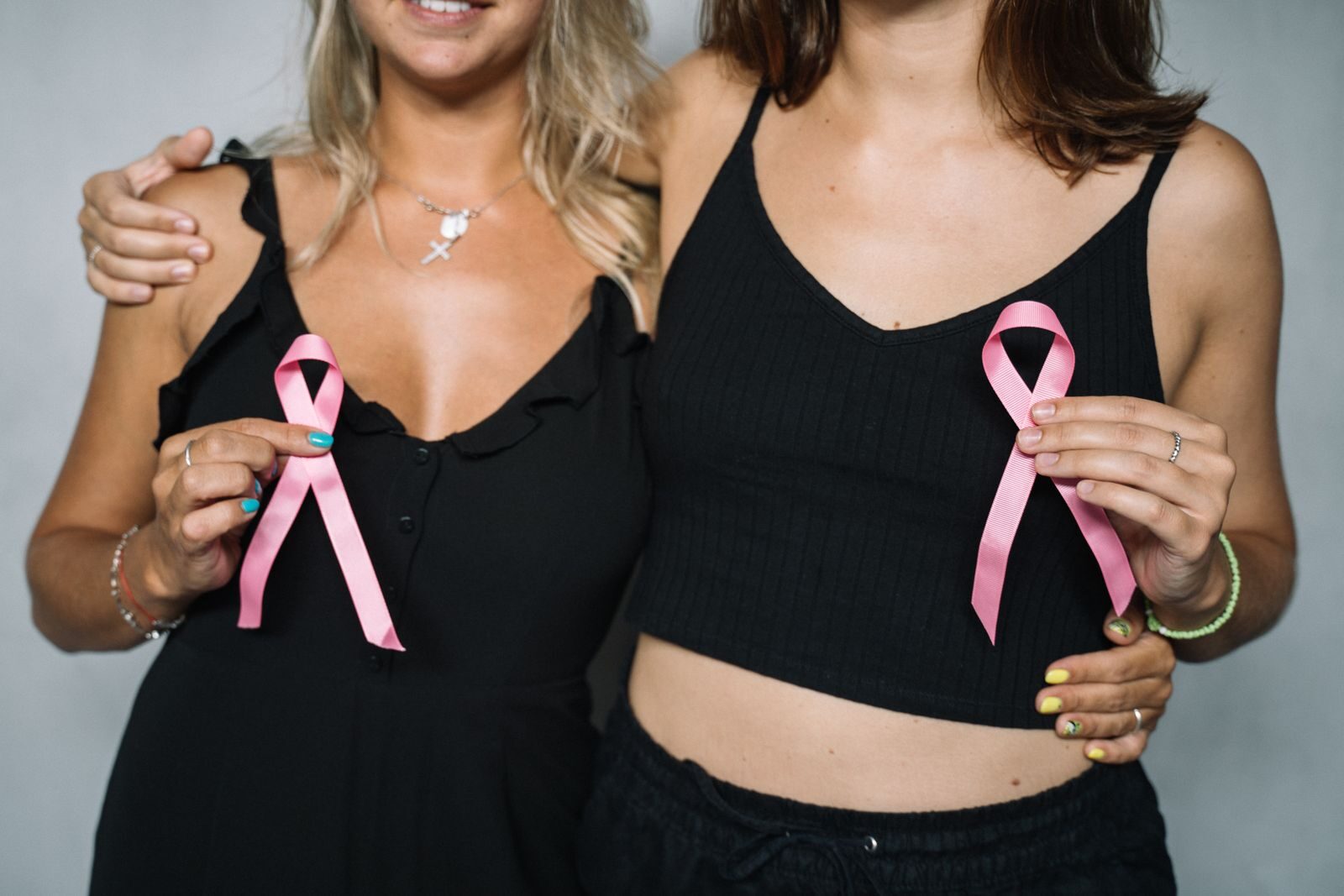 Duas mulheres segurando laços rosa em apoio à conscientização sobre a saúde da mama