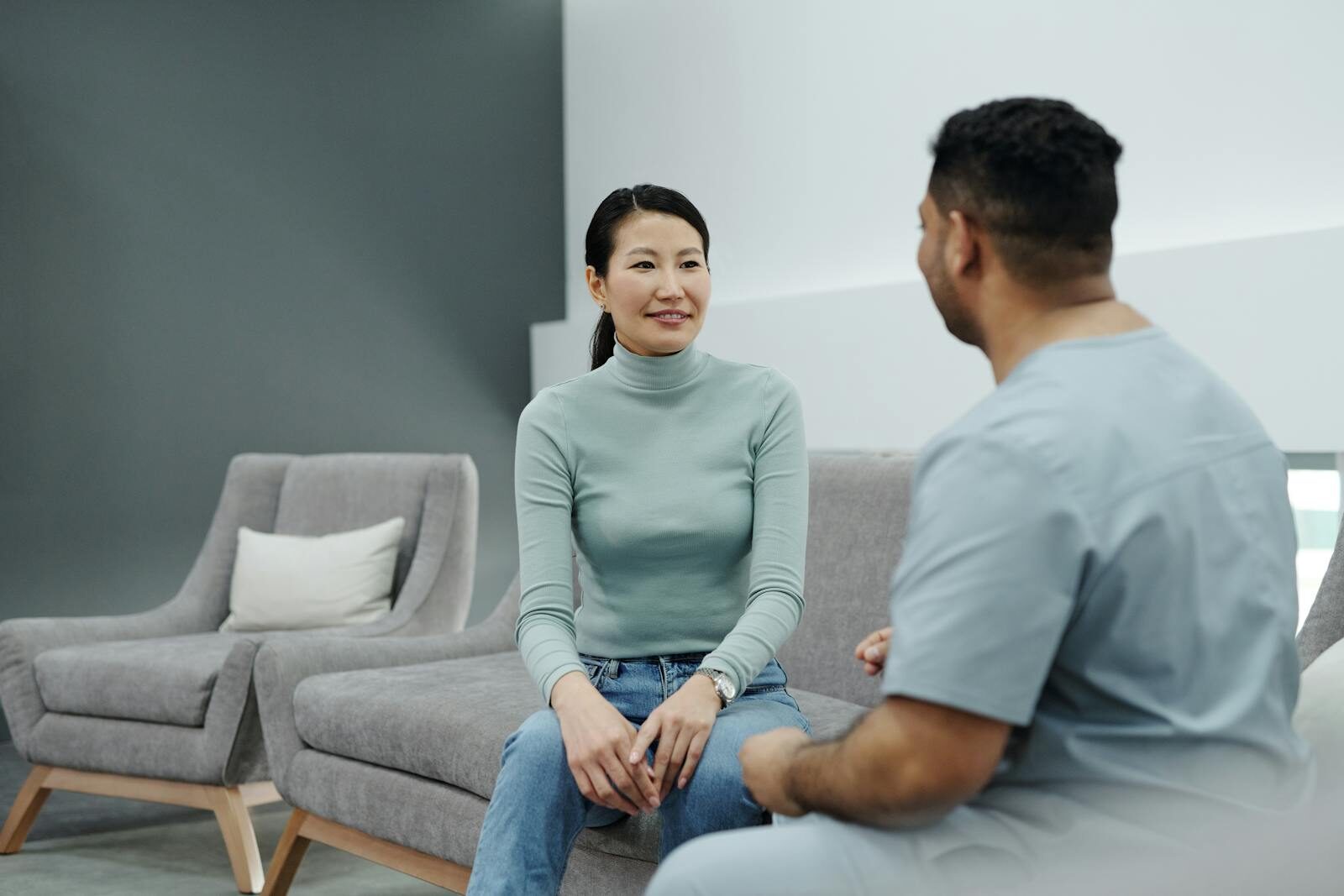 Médica conversa de forma acolhedora com uma paciente sorridente durante consulta em clínica bem iluminada