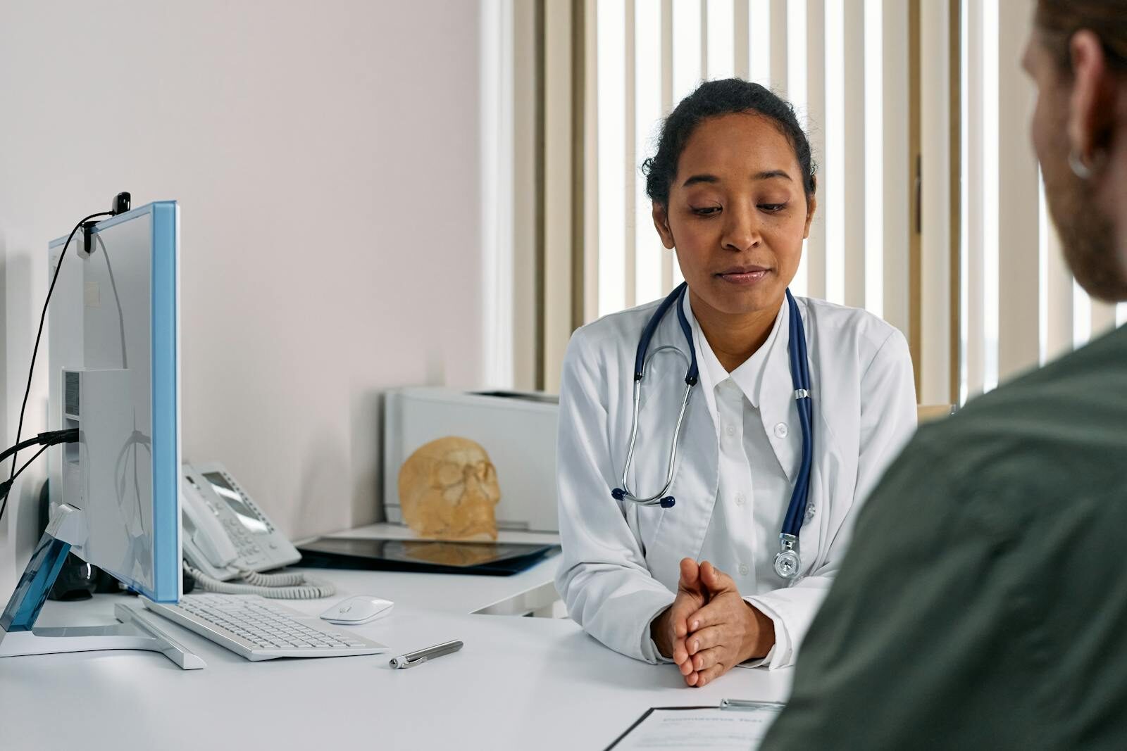 Ginecologista de jaleco branco conversando com uma paciente durante uma consulta em um consultório médico claro e moderno