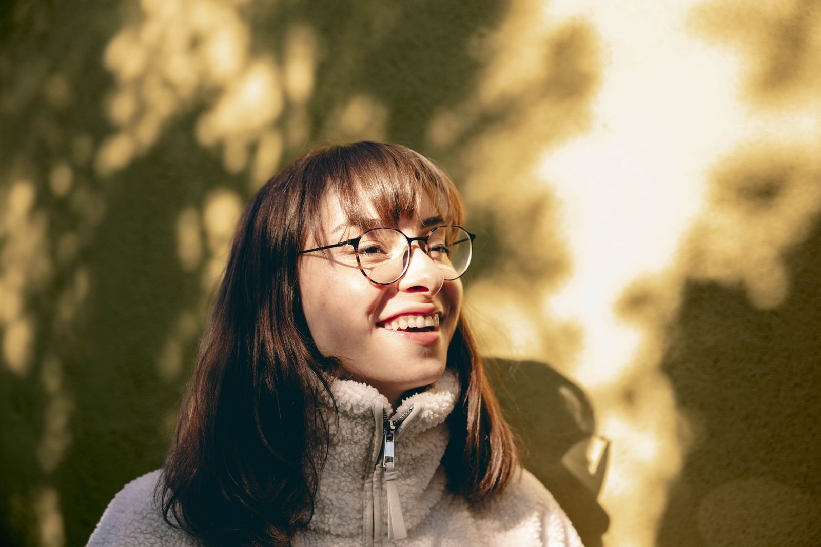Mulher jovem sorrindo ao ar livre sob a luz do sol, transmitindo bem-estar e confianca