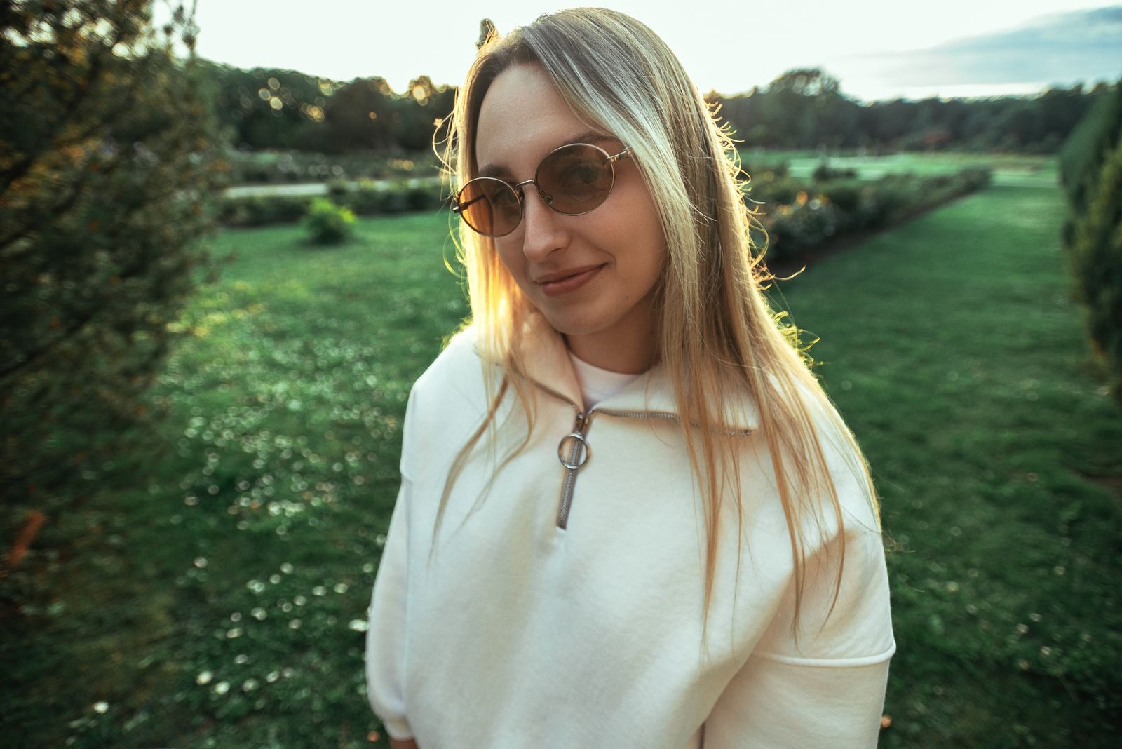 Mulher jovem sorrindo ao ar livre em um parque ensolarado, transmitindo bem-estar e liberdade no planejamento da contracepção