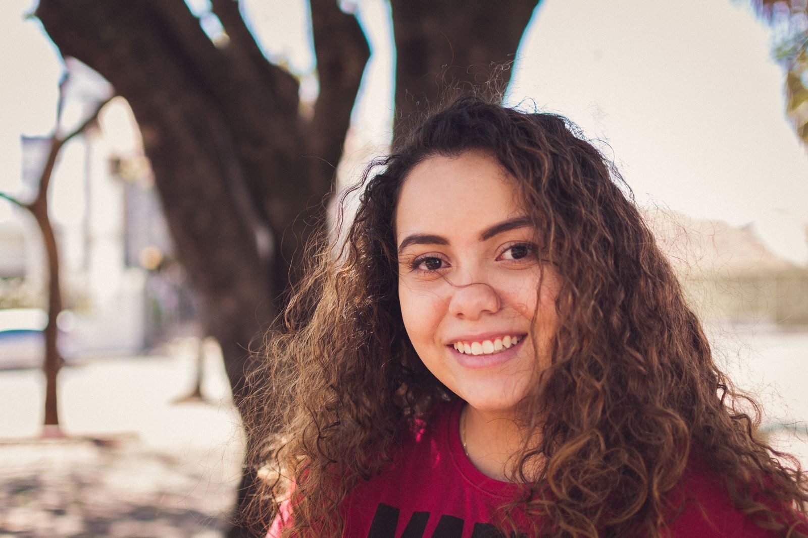 Mulher jovem sorrindo ao ar livre sob a luz do sol, transmitindo bem-estar e tranquilidade ao planejar a contracepção