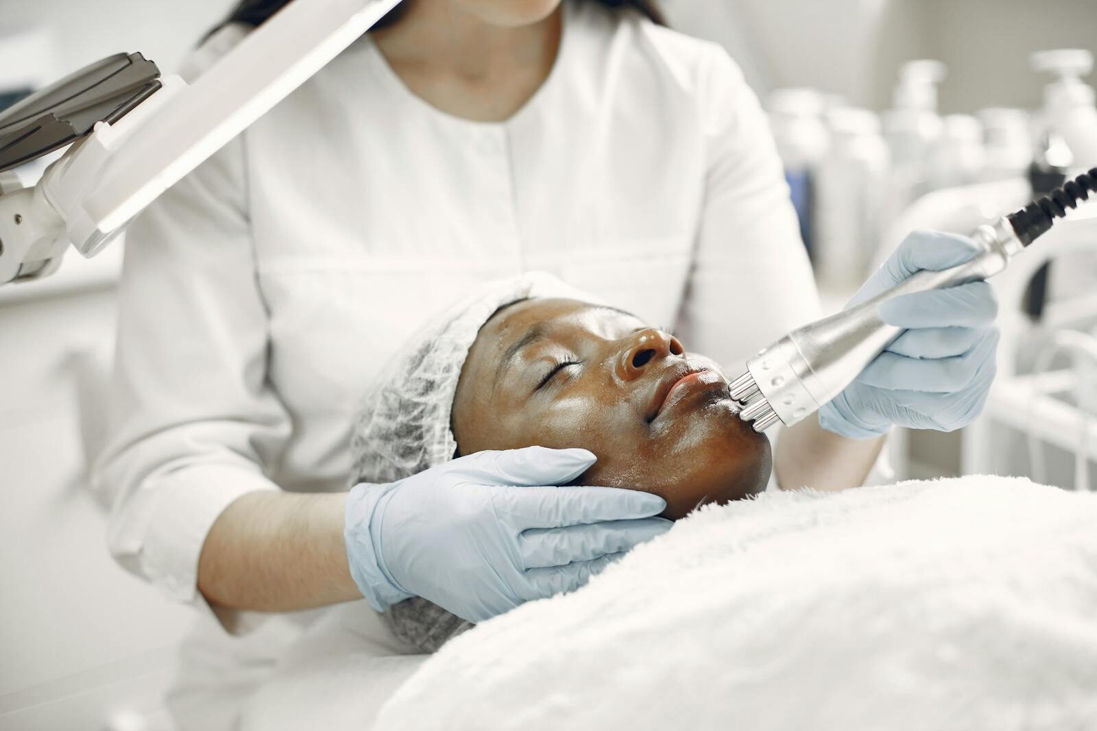Profissional de saúde realizando um procedimento de laser estético em uma paciente relaxada, em um consultório de clínica moderno e iluminado