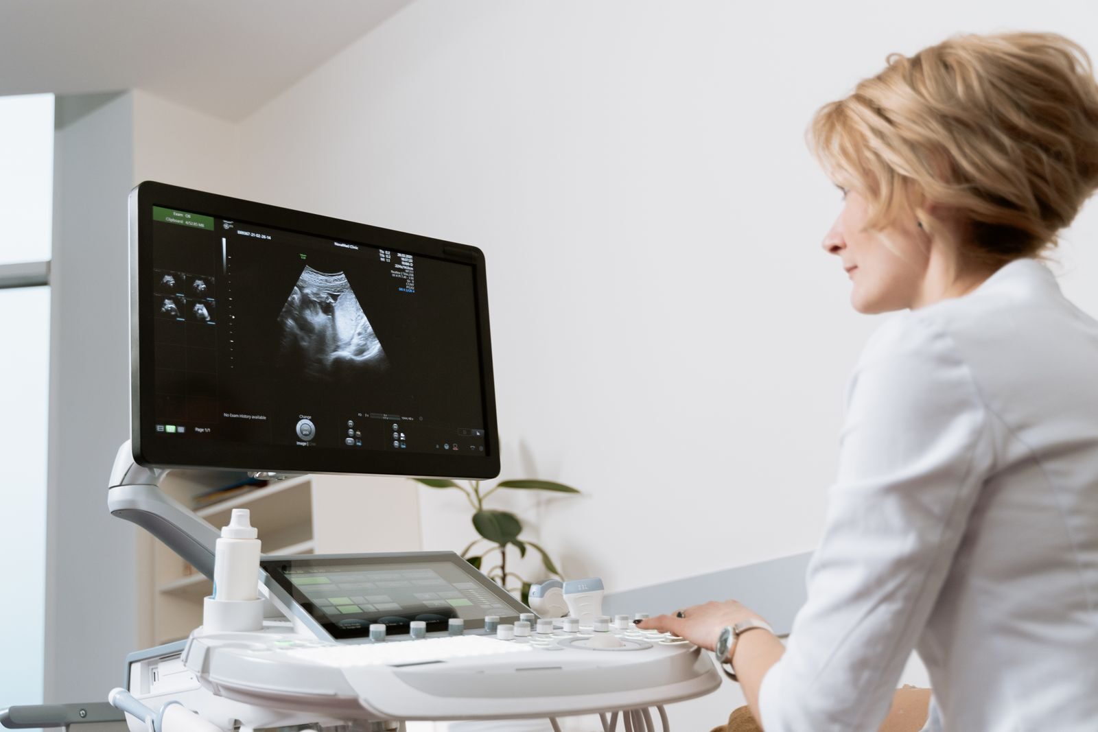 Médica realizando exame de ultrassom em equipamento moderno enquanto observa o monitor diagnóstico em uma clínica de saúde da mulher