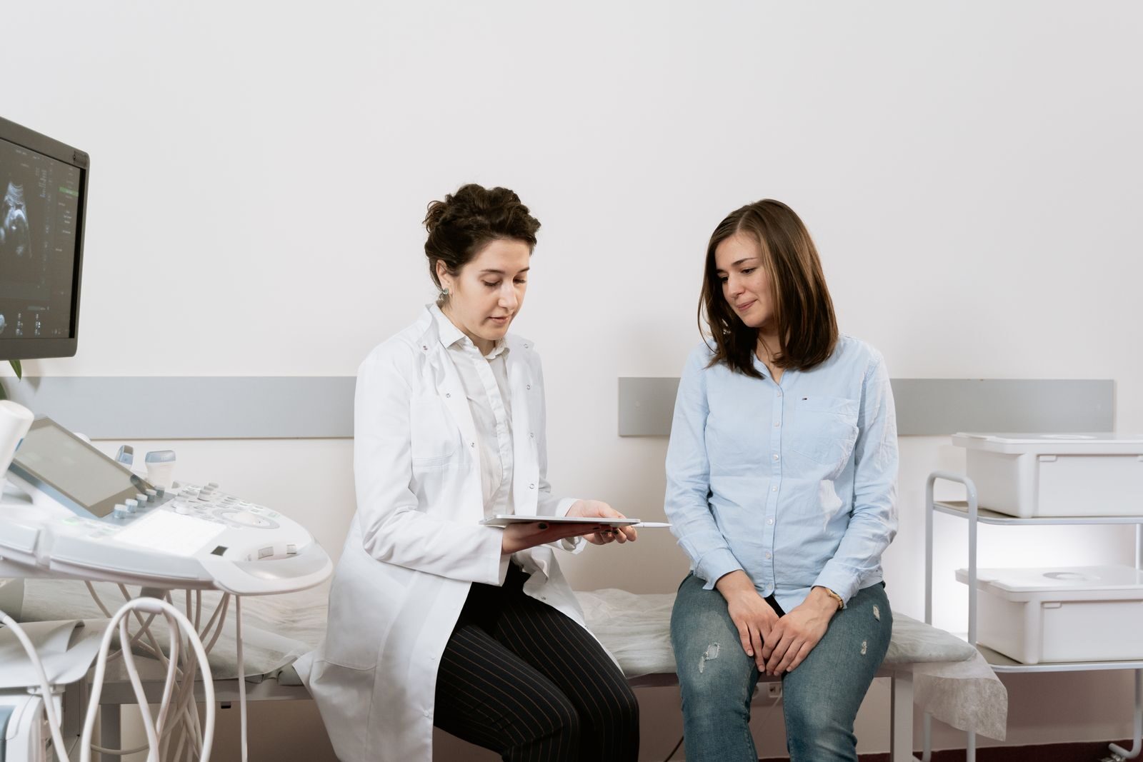Gestante sentada em consulta de pré-natal com médica ginecologista em consultório de clínica de saúde da mulher